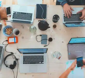 people sitting down near table with assorted laptop computers