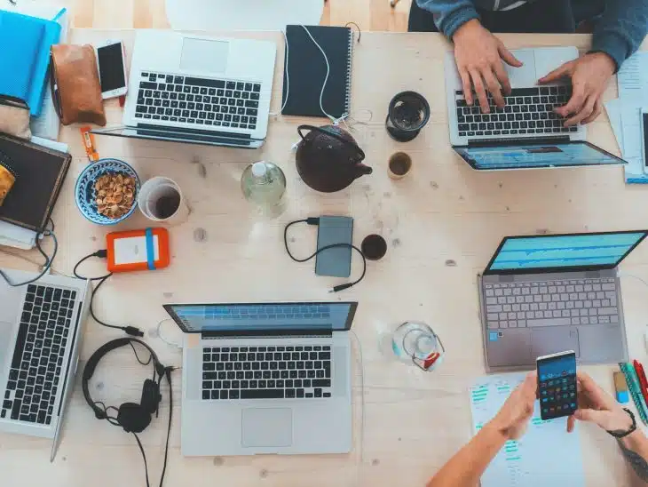 people sitting down near table with assorted laptop computers